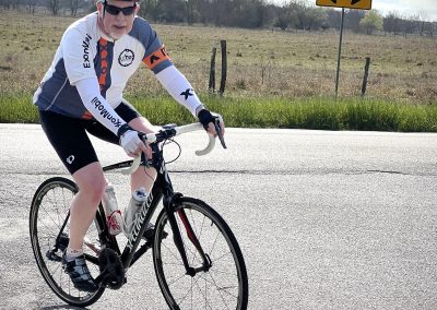 Cyclist on a bike ride along scenic rural roads, promoting Bluebonnet Express cycling events and outdoor adventure.