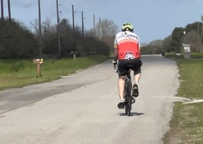 Rider cycling on a country road, showcasing Bluebonnet Express bike route, outdoor biking adventure, Texas scenery, eco-friendly transportation.
