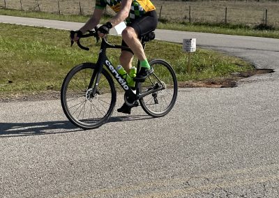 Vibrant cyclist riding a road bike in rural landscape during daytime.