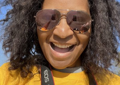 Bright sunny day with smiling woman wearing sunglasses and a yellow cycling jersey for Bluebonnet Express event.
