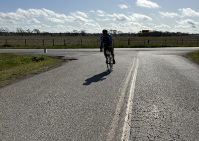 Cyclist riding on rural open road during sunny day for Bluebonnet Express biking tour.