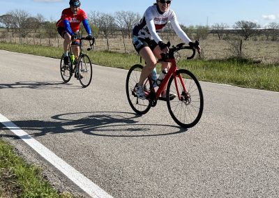 Vibrant cyclists riding on open road during a sunny day, promoting Bluebonnet Express cycling event.
