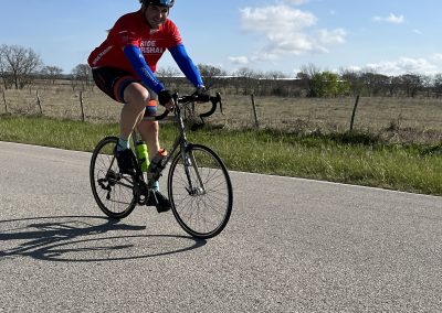 Cyclist riding National Park Service Bike Ride, Bluebonnet Express, on scenic rural road.