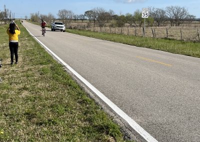 Open road with cyclists and support vehicle, demonstrating Bluebonnet Express cycling event.