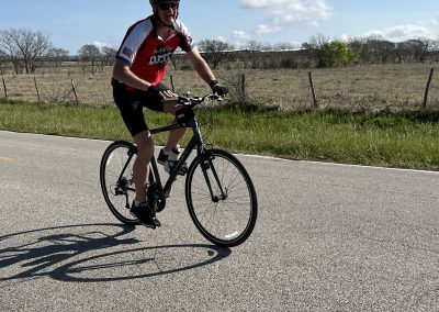 Vivid bike ride with cyclist on the open road in rural Texas under blue sky and scattered clouds.