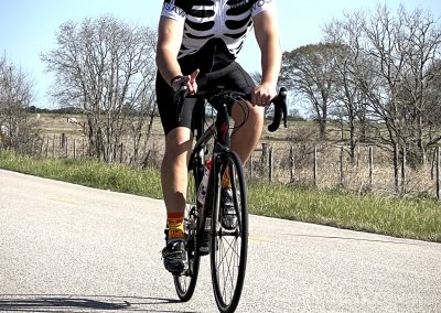 Vibrant cyclist riding on scenic rural road, showcasing Bluebonnet Express cycling tour.