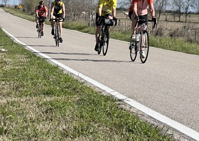Biking on scenic countryside road, group ride featuring Bluebonnet Express bikes, outdoor cycling adventure, Texas spring scenery, leisure bicycles.