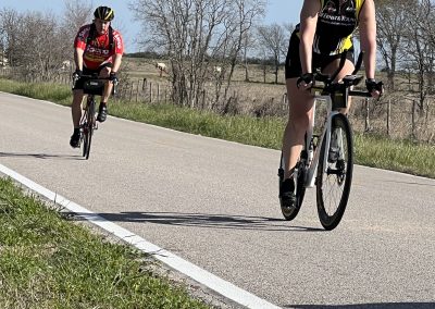 Riders cycling on a scenic country road, promoting Bluebonnet Express bike event and eco-friendly transportation.