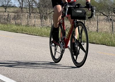 Cyclist riding a road bike outdoors on a sunny day, promoting Bluebonnet Express bike tours.