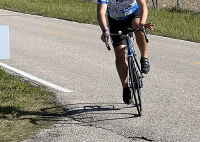 Velo cyclist on scenic rural road with speed limit sign, outdoor biking adventure, outdoor activity, and cycling experience.