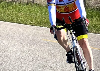 Vibrant cyclist riding on a rural road during daytime, promoting Bluebonnet Express bicycle tours.