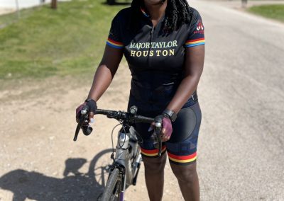 Bike rider in Major Taylor Houston cycling jersey, smiling with helmet and sunglasses, ready for a ride.