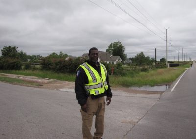 Police officer in high visibility vest on rural road during daytime.