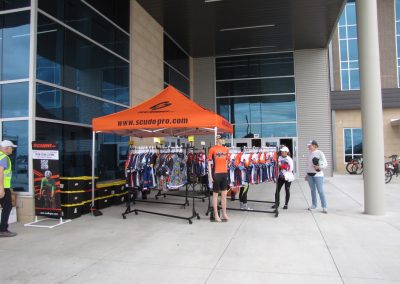 Orange cycling gear tent with apparel display at Bluebonnet Express event.