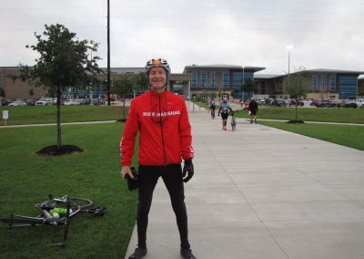 Brightly dressed Ride Marshal with bike in front of bluebonnet express paint building in Texas.