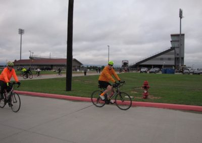 Bike riders on a trail at Bluebonnet Express, featuring stadium in the background.