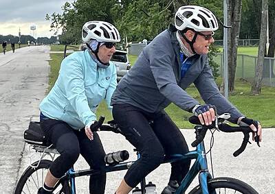 Cycling on a bike trail with two riders wearing helmets and outdoor gear, enjoying a scenic ride during cloudy weather.
