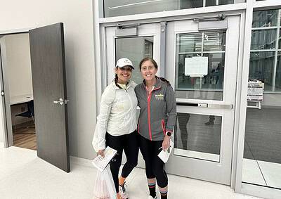 Athletes smiling in sportswear at airport entrance for Bluebonnet Express race.