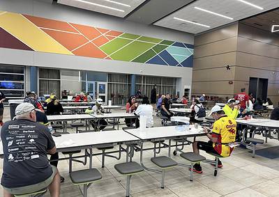 Vintage cyclists gathering at the Bluebonnet Express event indoor venue, socializing and preparing for a ride.