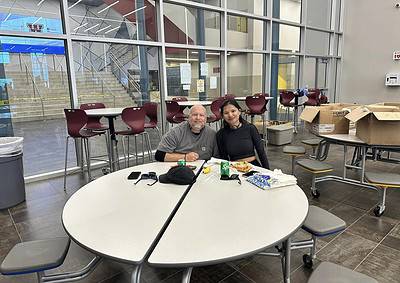 Bright indoor waiting area with two smiling people enjoying snacks and drinks, promoting Bluebonnet Express bicycle services.