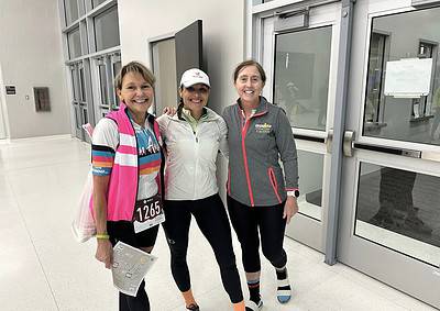 Smiling women at Ironman race finish line, celebrating athletic achievement and endurance.