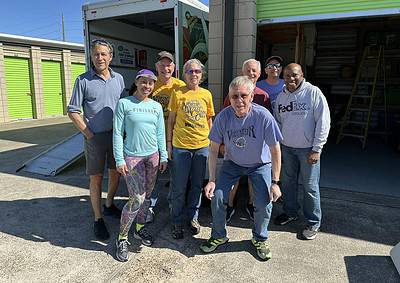 Group of smiling volunteers in front of a moving truck after a community event at Bluebonnet Express.