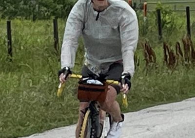 Cyclist riding a bike on a rural road, enjoying outdoor cycling adventure in lush countryside.