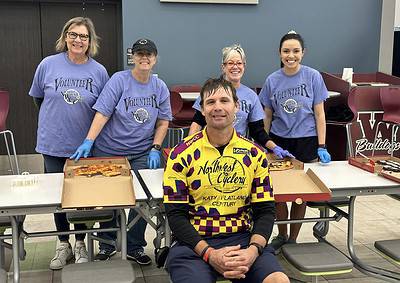 Happy volunteers at Bluebonnet Express cycling event, serving pizza and spreading community spirit.
