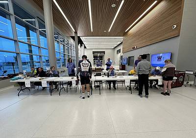 Bike registration and check-in at Bluebonnet Express event in a modern, well-lit indoor facility with volunteers and participants.