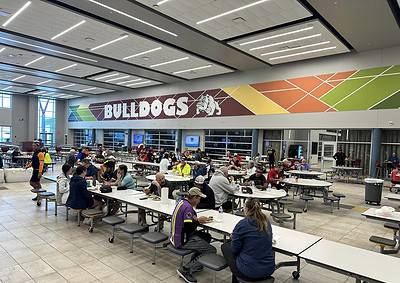 Bright indoor dining area at Bluebonnet Express, featuring a large "BULLDOGS" sign and many seated customers.