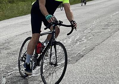 Bright yellow cycling jersey on male cyclist on scenic rural road during daytime.