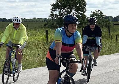 Brightly dressed cyclists riding along a rural road in the Bluebonnet Express event.