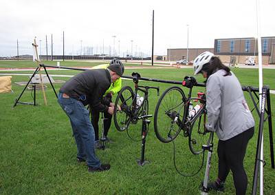 Bike repair station at Bluebonnet Express event with cyclists fixing bikes outdoors on a grassy field.
