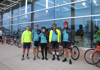 Bright cycling team outside Bluebonnet Express building, showcasing professional gear and bikes for scenic rides.