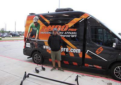 Cycling apparel delivery van with a cyclist graphic and "Bluebonnet Express" branding in a parking lot.