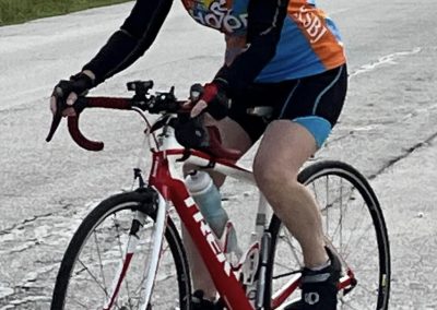 Vibrant blue and orange cyclist riding a Trek road bike on an open road during daytime.