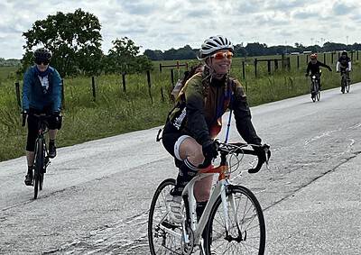 Bright female cyclist wearing helmet on road during Bluebonnet Express cycling event in Texas.
