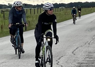Outdoor cyclists on scenic rural road promoting Bluebonnet Express bike tours and eco-friendly travel.