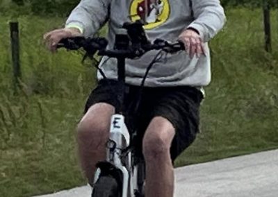 E-bike rider in casual gear on a scenic trail during daytime for Bluebonnet Express biking route.
