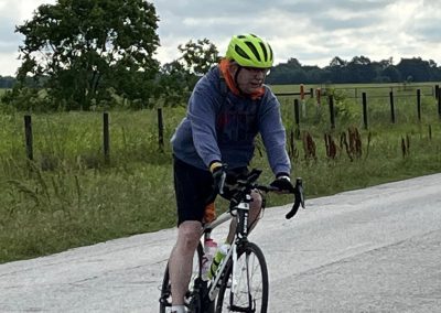 Bright green helmet on cyclist riding along rural road for Bluebonnet Express bike tour.