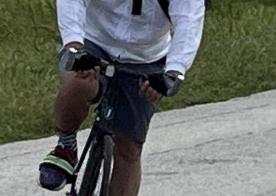 Rider on a black bicycle wearing a blue helmet, sunglasses, and casual athletic gear.