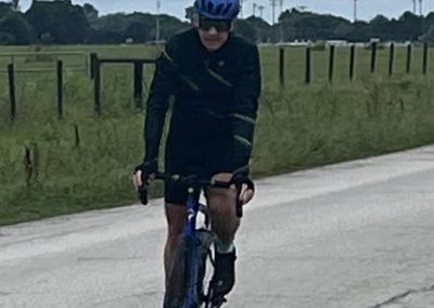 Bike rider wearing a blue helmet on a rural road with green fields, promoting Bluebonnet Express bike tours.