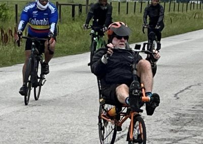 Bright blue cyclist jersey with "Colombia" logo, riding with friends on scenic country road.
