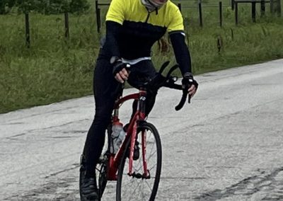 Vast cycling scene featuring a rider on a red bike amidst outdoor rural landscape, emphasizing endurance and adventure.