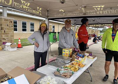 Supportive volunteers at Bluebonnet Express cycling event, providing food and drinks to participants.