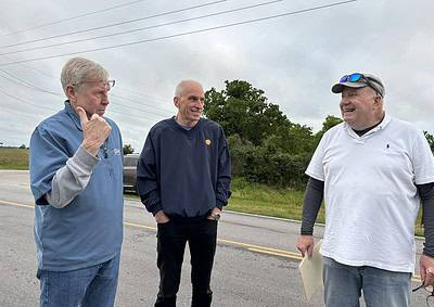 Older men talking outdoors on a cloudy day, likely discussing community or local topics.