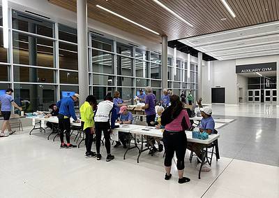 Event registration at Bluebonnet Express charity run, with participants and volunteers at indoor check-in tables.