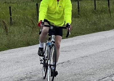 Cyclist wearing neon yellow jacket on rural road for Bluebonnet Express bike ride.