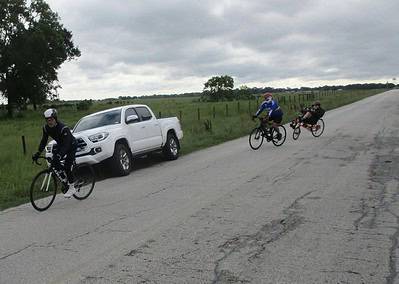 Bike ride along rural road with support vehicle, outdoor cycling, and scenic landscape.