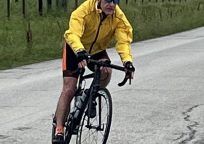 Vibrant cyclist in yellow jacket riding on rural road with safety gear and road bike.
